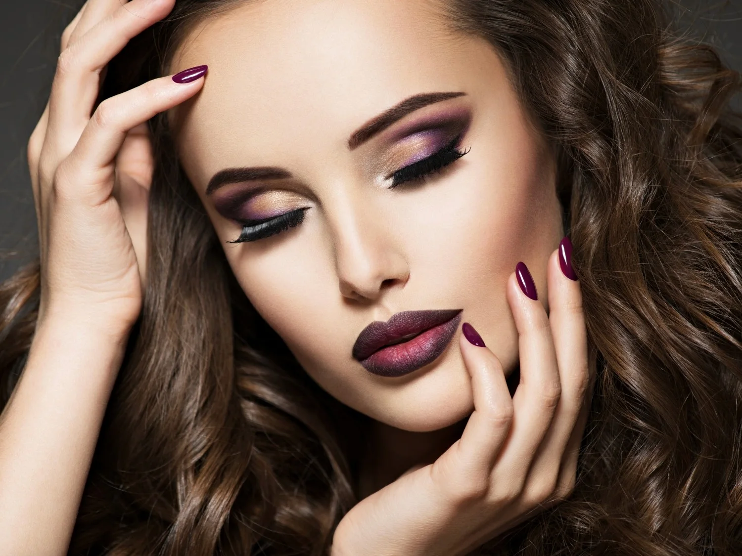 Modelo con maquillaje en tonos vino y cabello ondulado castaño